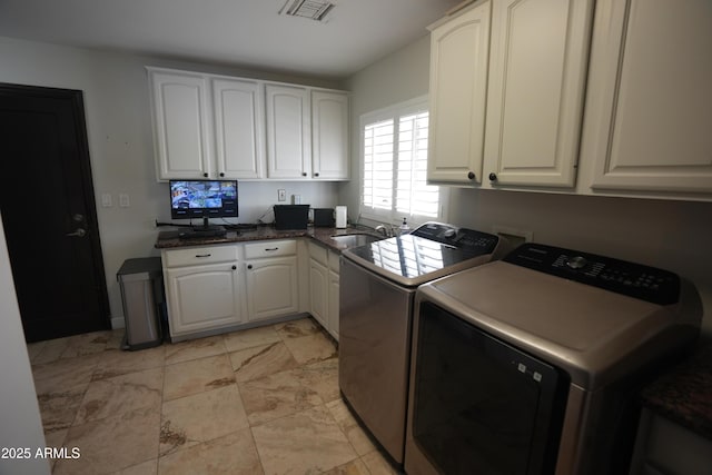 washroom with cabinets, sink, and washing machine and dryer