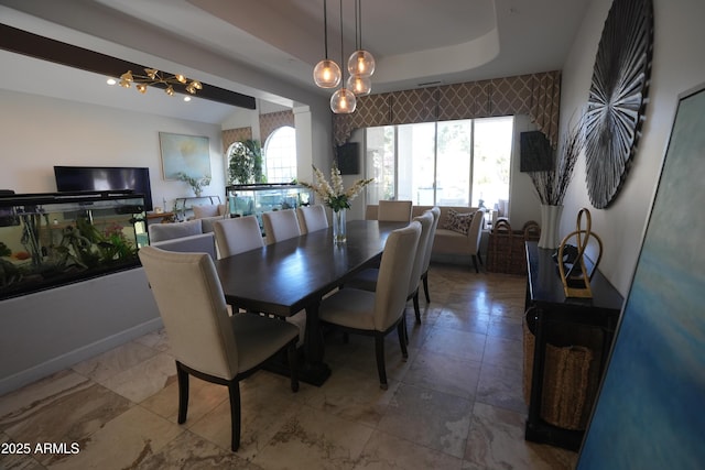 dining area with an inviting chandelier and a tray ceiling