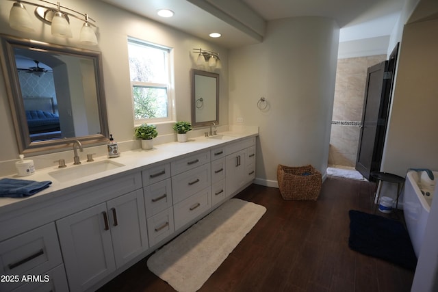 bathroom with ceiling fan, vanity, tiled shower, and hardwood / wood-style floors