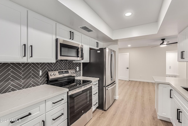 kitchen with backsplash, white cabinetry, light wood-type flooring, and appliances with stainless steel finishes