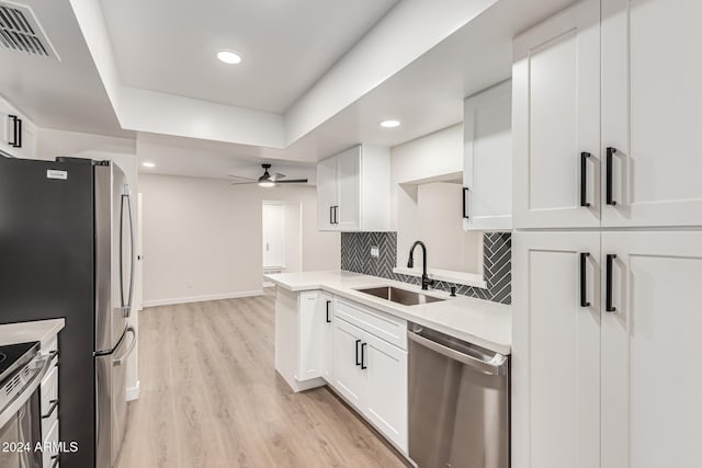 kitchen featuring appliances with stainless steel finishes, light wood-type flooring, white cabinetry, and sink