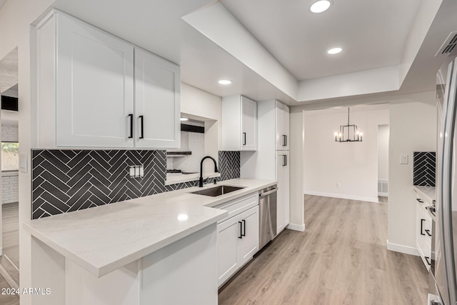 kitchen featuring backsplash, white cabinetry, pendant lighting, and light wood-type flooring