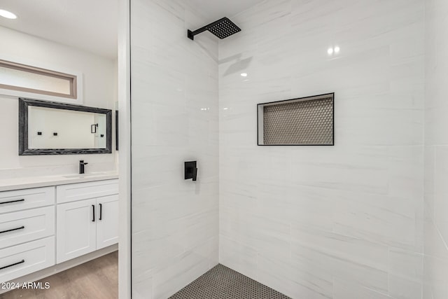 bathroom featuring hardwood / wood-style floors, vanity, and a tile shower