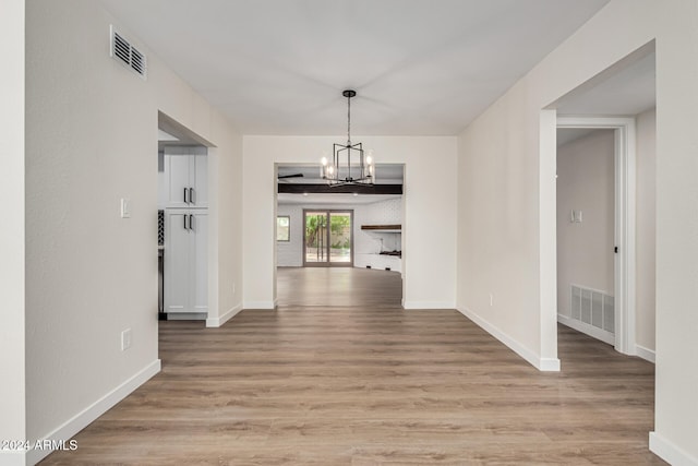 hall featuring light wood-type flooring and a chandelier