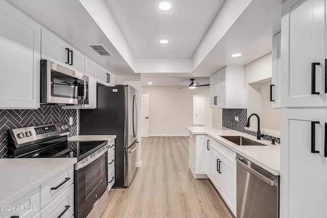 kitchen featuring sink, light hardwood / wood-style flooring, ceiling fan, appliances with stainless steel finishes, and white cabinetry