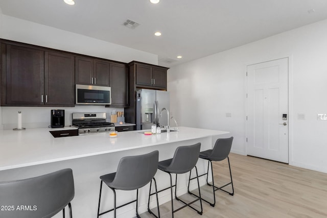 3885 E Kenley Ln, San Tan Valley, AZ 85143 - kitchen with appliances with stainless steel finishes, dark brown cabinets, light countertops, recessed lighting, and a kitchen breakfast bar