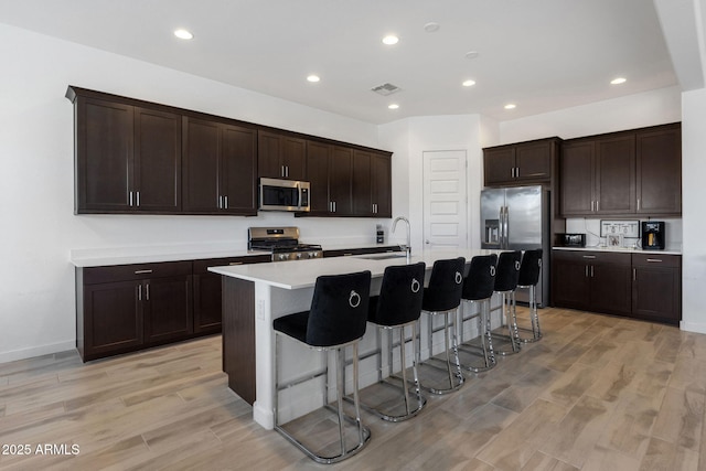 3885 E Kenley Ln, San Tan Valley, AZ 85143 - kitchen with stainless steel appliances, a sink, a breakfast bar, light countertops, and a center island with sink