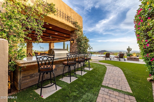 4328 N Pinnacle Ridge Cir, Mesa, AZ 85207 - view of grassy yard featuring a fire pit, a patio area, a ceiling fan, and an outdoor kitchen