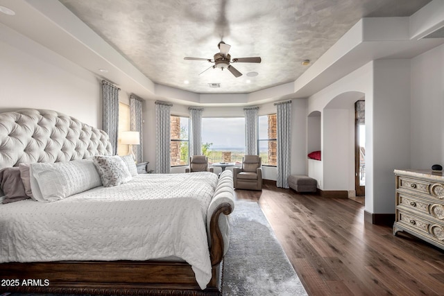 4328 N Pinnacle Ridge Cir, Mesa, AZ 85207 - bedroom with arched walkways, dark wood-style flooring, baseboards, ceiling fan, and a tray ceiling