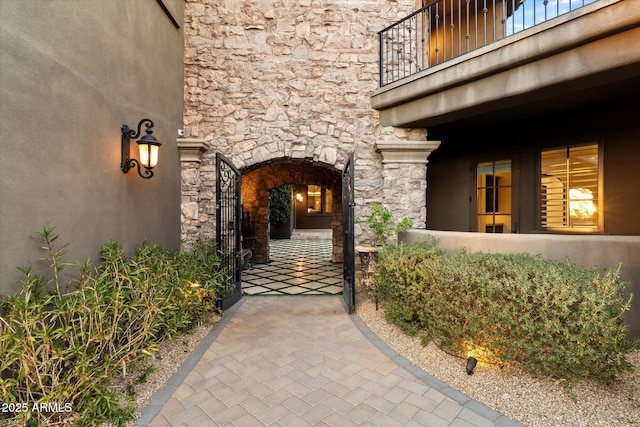 view of exterior entry with stone siding and a balcony