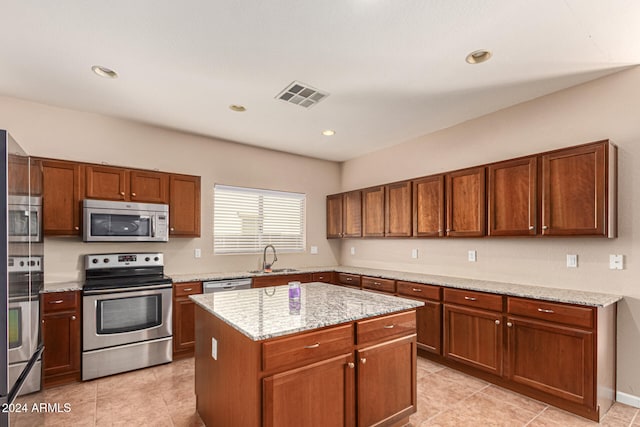 kitchen featuring light stone countertops, sink, light tile patterned flooring, a kitchen island, and appliances with stainless steel finishes