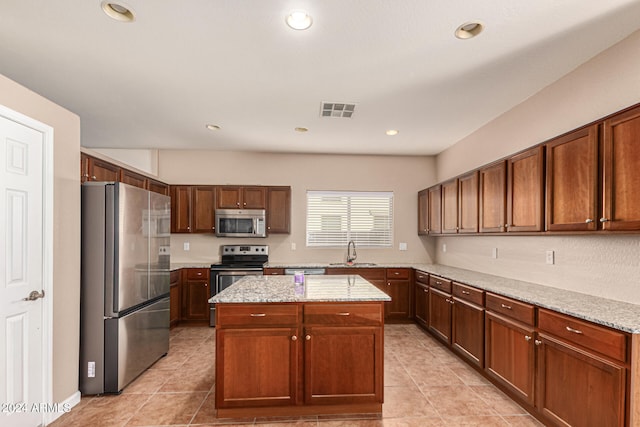 kitchen with light tile patterned flooring, light stone counters, a kitchen island, and stainless steel appliances