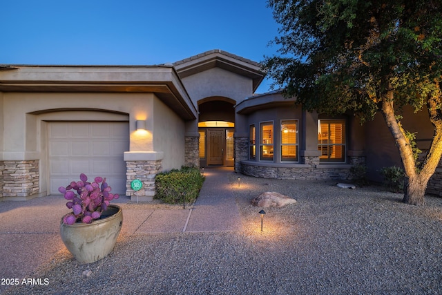 view of front facade featuring stone siding, an attached garage, and stucco siding