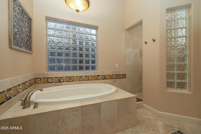 bathroom with a garden tub, baseboards, and walk in shower