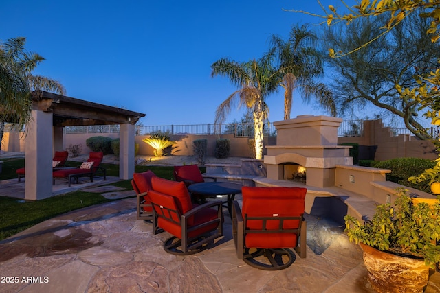 view of patio with a warm lit fireplace and a fenced backyard