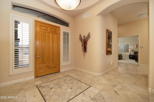 entrance foyer featuring arched walkways, visible vents, and baseboards