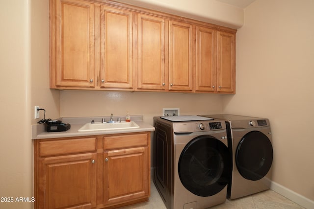 laundry area featuring washing machine and clothes dryer, a sink, cabinet space, and baseboards