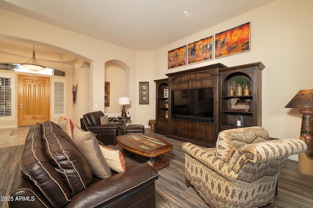 living area with arched walkways and dark wood-style flooring