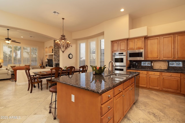 kitchen with open floor plan, appliances with stainless steel finishes, a breakfast bar, and brown cabinets