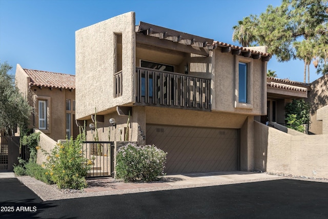 4434 E Camelback Rd Unit 132, Phoenix, AZ 85018 - view of front of house with a balcony, an attached garage, stucco siding, a tiled roof, and driveway