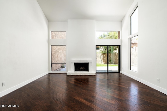 4434 E Camelback Rd Unit 132, Phoenix, AZ 85018 - unfurnished living room featuring a brick fireplace, wood-type flooring, and a towering ceiling