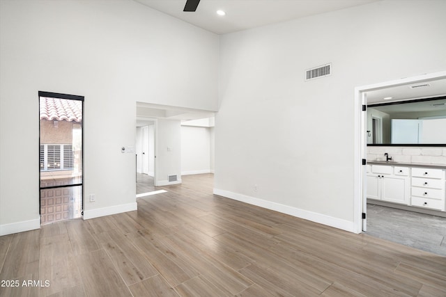 4434 E Camelback Rd Unit 132, Phoenix, AZ 85018 - unfurnished living room with a towering ceiling, ceiling fan, light wood-style floors, and recessed lighting