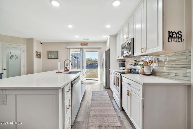 kitchen featuring white cabinets, sink, light stone countertops, appliances with stainless steel finishes, and light hardwood / wood-style floors