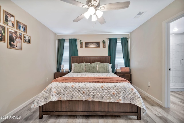 bedroom featuring multiple windows, ensuite bathroom, and hardwood / wood-style flooring