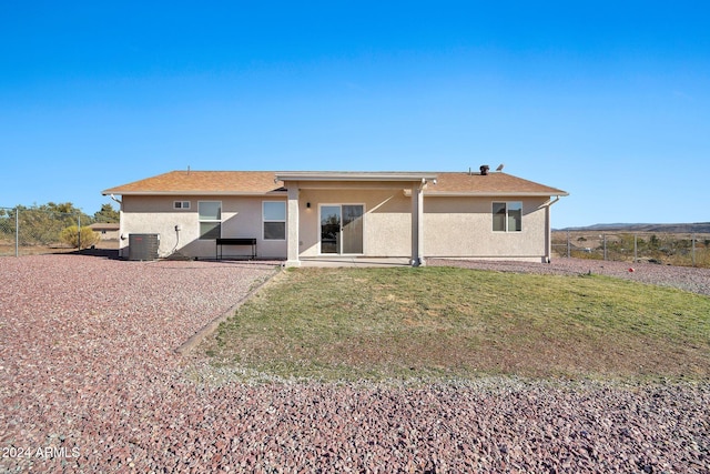 rear view of property featuring a patio, a yard, and central AC