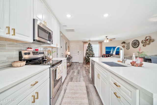 kitchen featuring white cabinets, sink, ceiling fan, light wood-type flooring, and stainless steel appliances