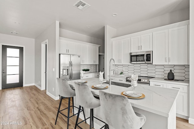 kitchen featuring white cabinetry, a breakfast bar, an island with sink, and stainless steel appliances