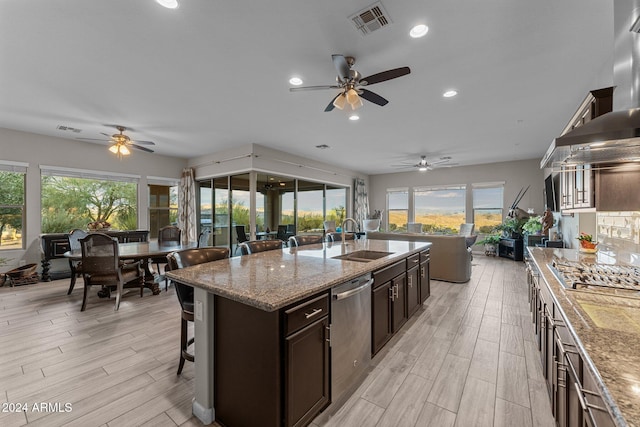 kitchen featuring a kitchen island with sink, a kitchen breakfast bar, sink, light wood-type flooring, and appliances with stainless steel finishes