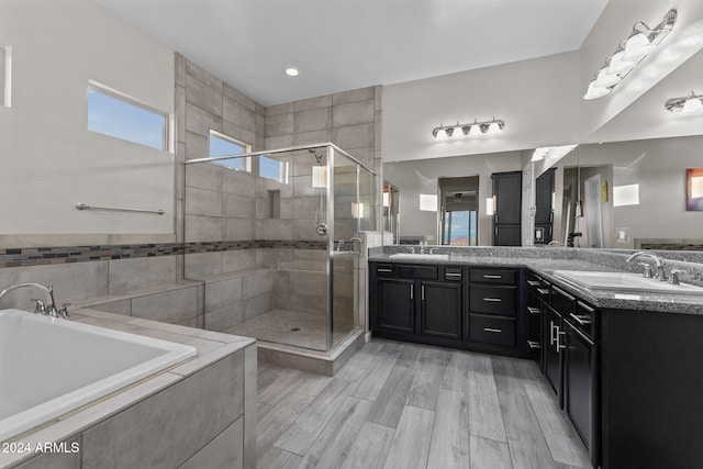 bathroom featuring shower with separate bathtub, vanity, hardwood / wood-style flooring, and tile walls