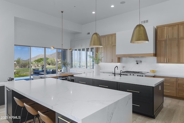 kitchen featuring a mountain view, visible vents, wall chimney range hood, a spacious island, and backsplash