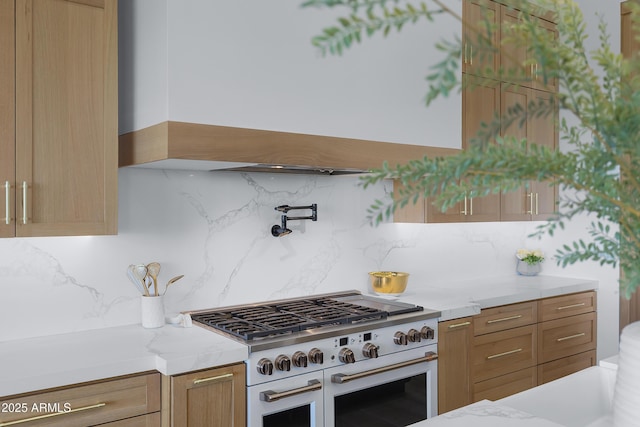 kitchen featuring backsplash, range with two ovens, and light stone countertops