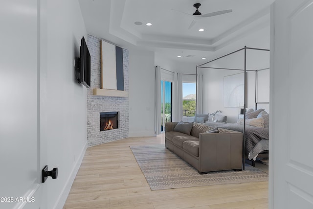 bedroom with light wood-type flooring, access to exterior, a brick fireplace, and recessed lighting