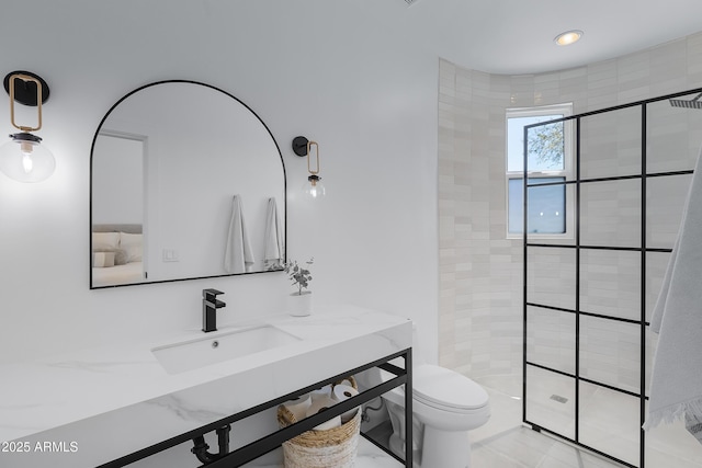 bathroom featuring toilet, tiled shower, and a sink