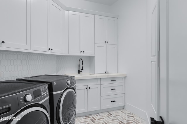 laundry room with baseboards, washer and dryer, a sink, brick floor, and cabinet space