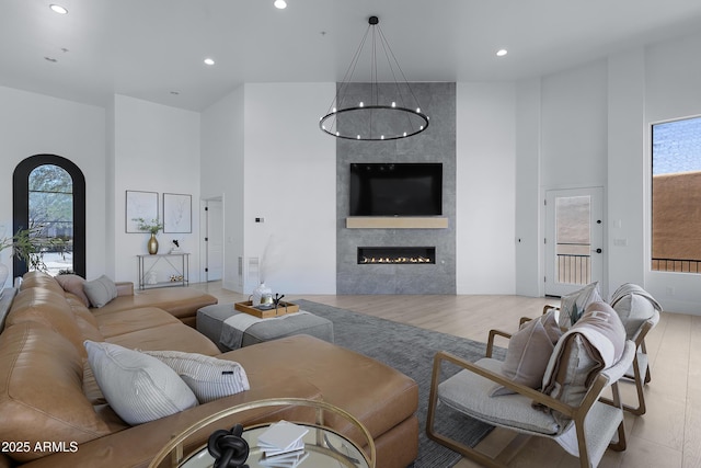 living room featuring wood finished floors, a fireplace, a towering ceiling, and recessed lighting