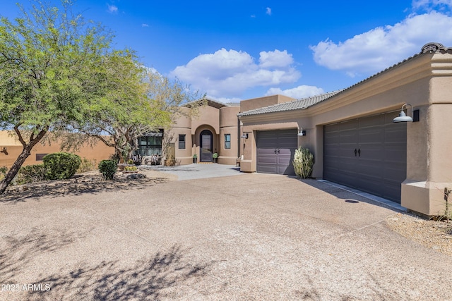 mediterranean / spanish-style house with a tile roof, driveway, a garage, and stucco siding