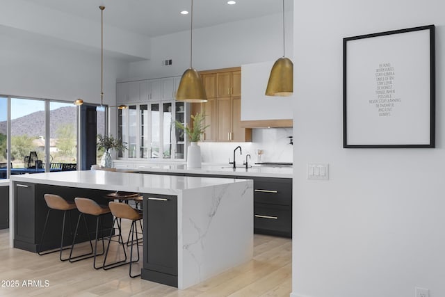 kitchen with a mountain view, light wood-style flooring, a kitchen island, a sink, and hanging light fixtures