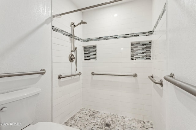 bathroom featuring a tile shower and toilet