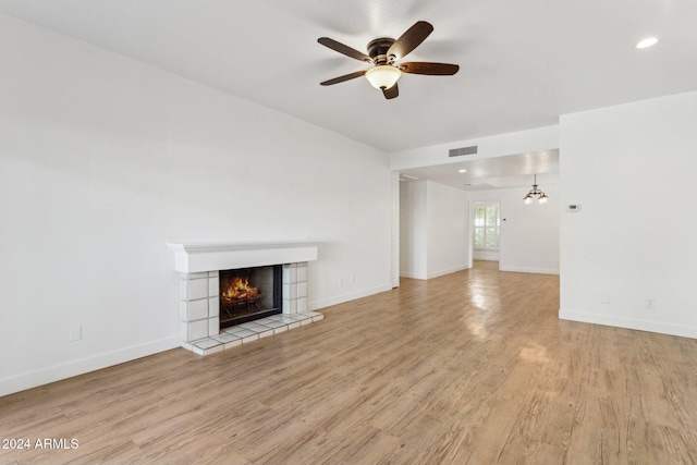 unfurnished living room featuring a fireplace, light wood-type flooring, and ceiling fan