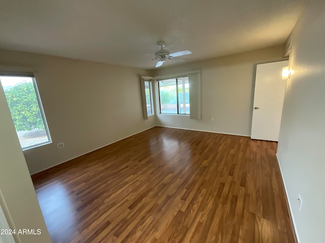 spare room with a wealth of natural light, dark hardwood / wood-style floors, and ceiling fan