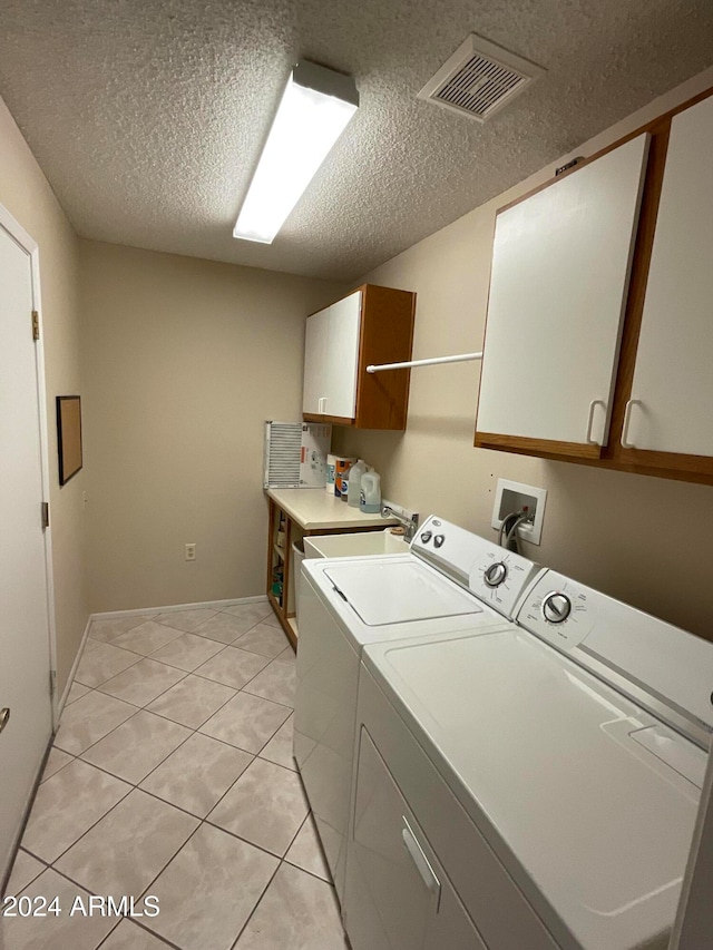 laundry room with cabinets, light tile patterned flooring, separate washer and dryer, sink, and a textured ceiling