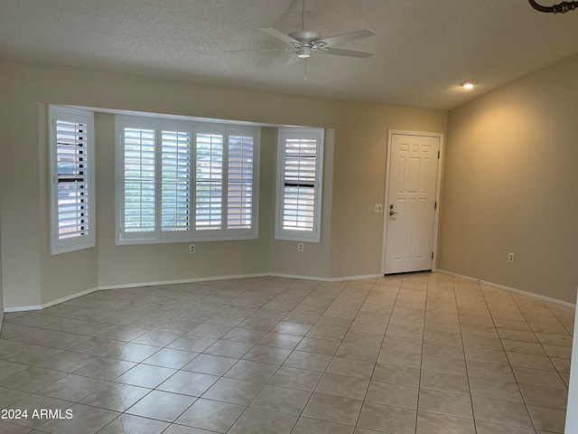 spare room featuring ceiling fan, a textured ceiling, and light tile patterned floors