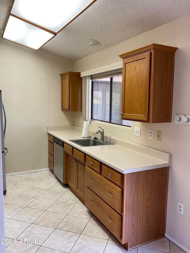 kitchen with a textured ceiling, sink, light tile patterned flooring, and stainless steel appliances