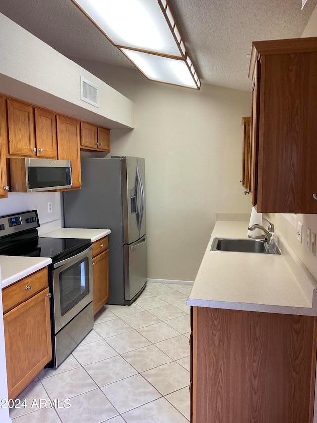 kitchen featuring a textured ceiling, appliances with stainless steel finishes, sink, and light tile patterned floors