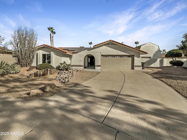 mediterranean / spanish-style house featuring stucco siding, concrete driveway, roof mounted solar panels, a garage, and a tiled roof