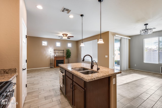 kitchen featuring ceiling fan, sink, light hardwood / wood-style floors, decorative light fixtures, and a kitchen island with sink